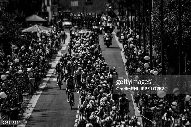 Spectators wave while holding bicycle wheels to form a guard of honor as the pack rides during the fourth stage of the 105th edition of the Tour de...