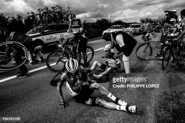 France's Axel Domont and Poland's Tomasz Marczynski grimace after being caught in a massive pack fall in the last kilometers of the fourth stage of...