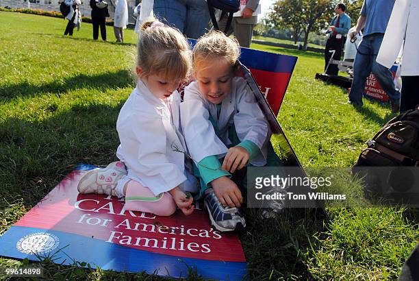 Madison and Morgan Gabrielson of Alabama, huddle under signs at a rally by the American Academy of Family Physicians to urge voters to make the next...
