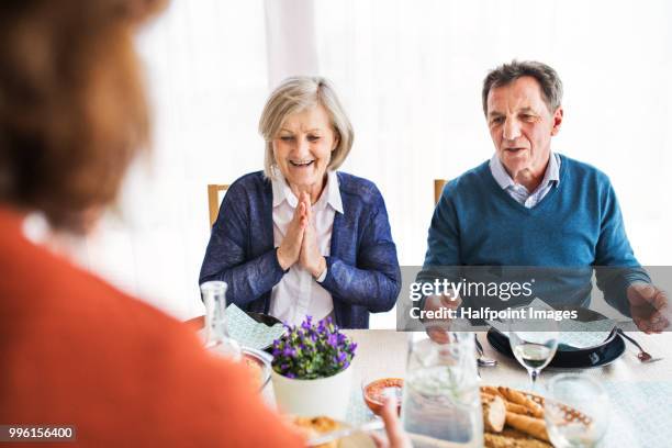 group of senior friends eating dinner together at home. - halfpoint stock-fotos und bilder