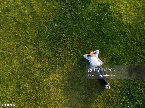 joven relajada durmiendo sobre la hierba - acostado fotografías e imágenes de stock