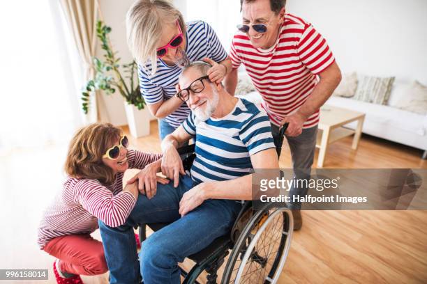 two senior couples with wheelchair having fun at a party at home. - halfpoint stockfoto's en -beelden