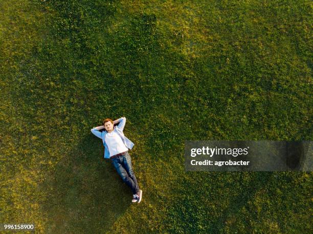 entspannte junger mann schlafen auf gras - im gras liegen stock-fotos und bilder