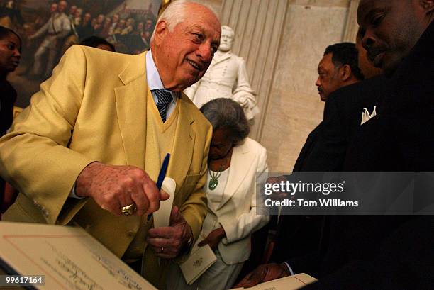 Tommy Lasorda, signs a certificate after a Congressional Gold Medal that was posthumously given to baseball player Jackie Robinson, at a ceremony in...