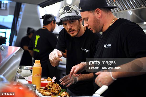 Spike Mendelsohn, center, owner of Good Stuff Eatery and Mike Colletti, general manager, make hamburgers during the media preview before the...