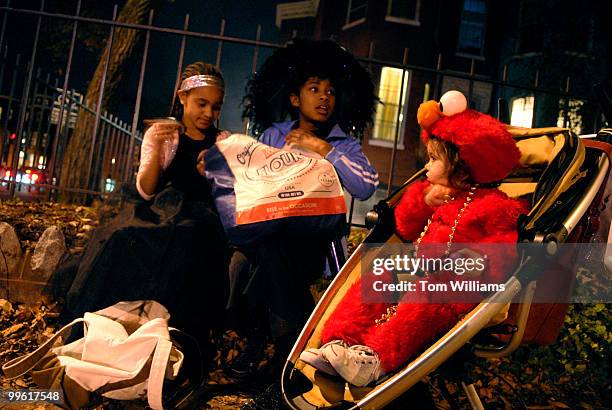 Yasmeen Butler left, and Aliyah Sola go through their candy as Azadeh Reiskin looks on, near Lincoln Park on East Capitol Street on Halloween night.