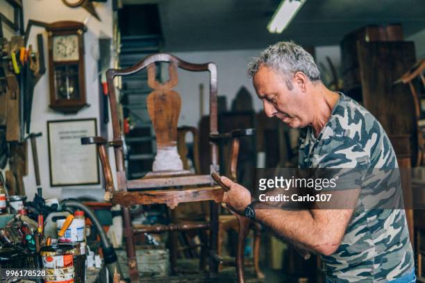 timmerman herstel van een oude houten stoel - carlo107 stockfoto's en -beelden