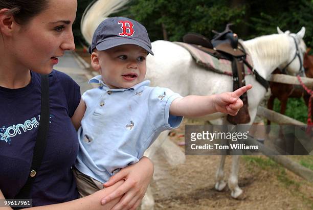 Aiden Kohn Murphy, 18 months, points at a horse in the arms of au pair Annelise Jackson, at Rock Creek Park Horse Center.