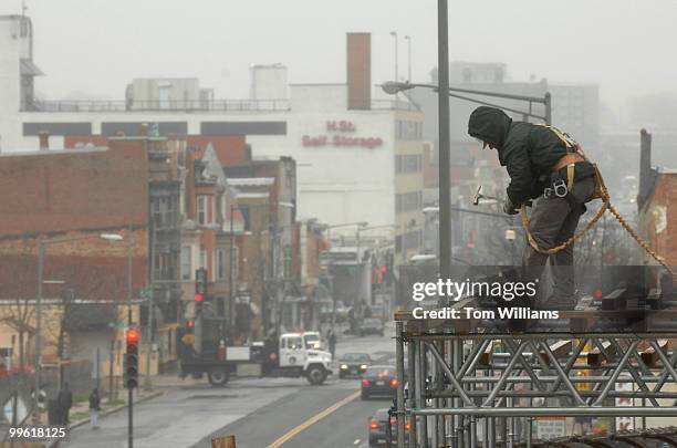 Worker hammers scaffolding connected to construction on a new wing of the Securities and Exchange Commission building along H Street, NE.