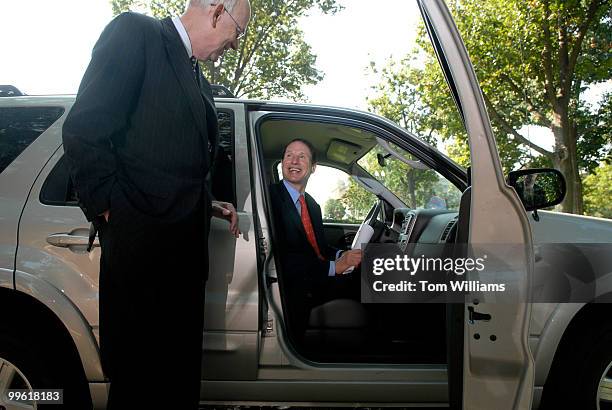 Sen. Ron Wyden, D-Ore., sits in the Ford Escape hybrid of Bob Bennett, R-Utah, left, at a news conference in which they proposed a plan that would...