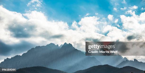 sun through clouds against mountains, silhouette of the mountains with monte cinto, col de vergio, cinto massif, corsica, france - cinto stock-fotos und bilder