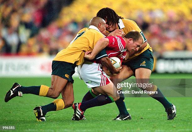 Matt Dawson of the Bristish and Lions is tackled by Geroge Gregan and George Smith of Australia during the third and final Test Match played between...