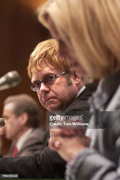 Musician Elton John listens to the testimony of Sandy Thurman, president of the International AIDS Trust, on the world wide AIDS epidemic, in front...