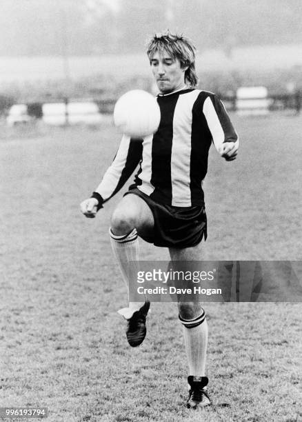 Singer Rod Stewart playing football in a striped shirt, possibly of Brentford FC, early 1980s.