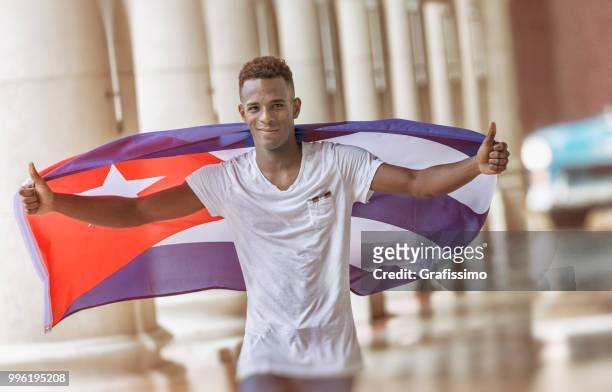 kubanische mann zu fuß mit kubanischen flagge durch alt-havanna - grafissimo stock-fotos und bilder