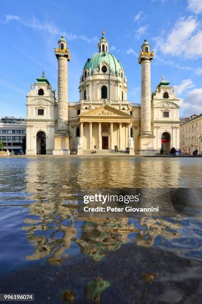 baroque karlskirche church designed by johann bernhard fischer von erlach, with reflections in the water basin, karlsplatz square, vienna, austria - karlskirche stock-fotos und bilder