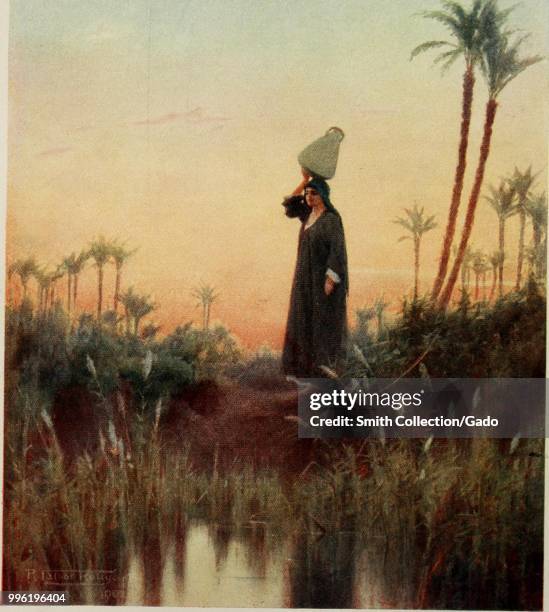 Color print of a woman, wearing a jellabiya and a scarf and balancing a jug on her head as she walks in an alluvial landscape, presumably the Nile...
