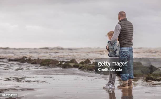 alleinerziehender vater und seine tochter familie spielen an einem winter-strand - mourning stock-fotos und bilder