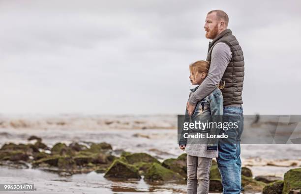 single father and his daughter playing family games on a winter beach - mourner stock pictures, royalty-free photos & images