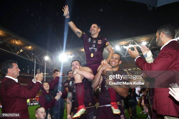 Billy Slater of Queensland waves to the crowd as he is chaired from the field by Cameron Munster and Will Chambers of Queensland after his final game...