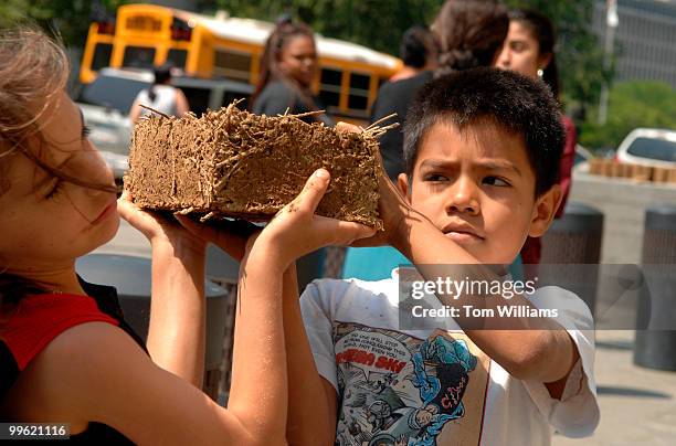 Ellezer Morales Lopez passes a brick made of mud and hay to Kalin Steen for an outdoor sculpture near the National Museum of the American Indian, by...