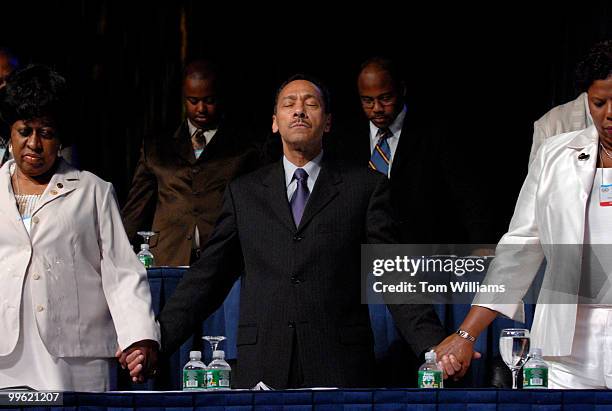 Rep. Mel Watt, D-N.C., center, holds hands with Rovenia Vaughan, left, and Lorraine Miller, during a prayer at the 97th annual NAACP Convention at...