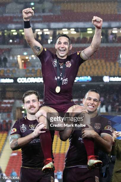 Billy Slater of Queensland waves to the crowd as he is chaired from the field by Cameron Munster and Will Chambers of Queensland after his final game...