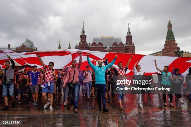 Crotian football fans shelter from a downpour under a giant Croatian flag near Red Square ahead of tonight's World Cup semi-final game between...