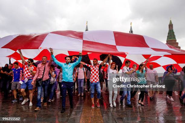 Crotian football fans shelter from a downpour under a giant Croatian flag near Red Square ahead of tonight's World Cup semi-final game between...