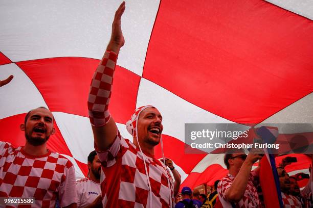 Crotian football fans shelter from a downpour under a giant Croatian flag near Red Square ahead of tonight's World Cup semi-final game between...