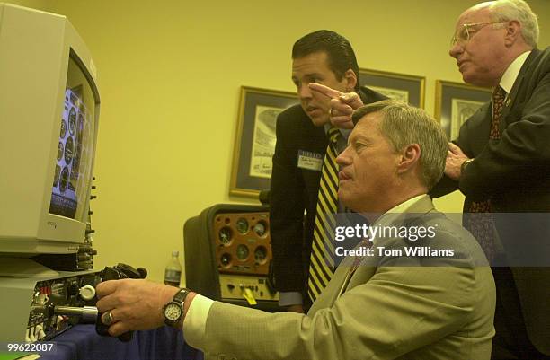 John Williams of the Aircraft Owner and Pilots Association and Rep. Vern Ehlers assist Rep. Collin Peterson as he tries out a new flight simulator....