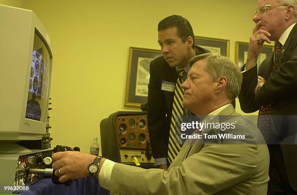 John Williams of the Aircraft Owner and Pilots Association and Rep. Vern Ehlers assist Rep. Collin Peterson as he tries out a new flight simulator....