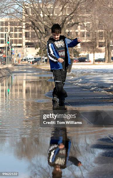 Jay Rogers of Denver, negotiates a puddle along 3rd Street near the west front. Temperatures on Wednesday reached the mid 50's.