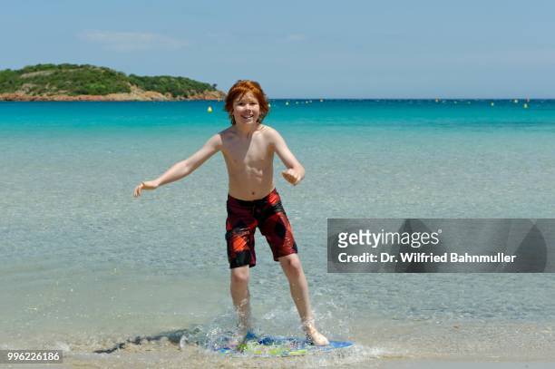 boy surfing with his boogie board, beach board or skimboard on the beach, bay of rondinara, southeast coast, corsica, france - rondinara stock pictures, royalty-free photos & images