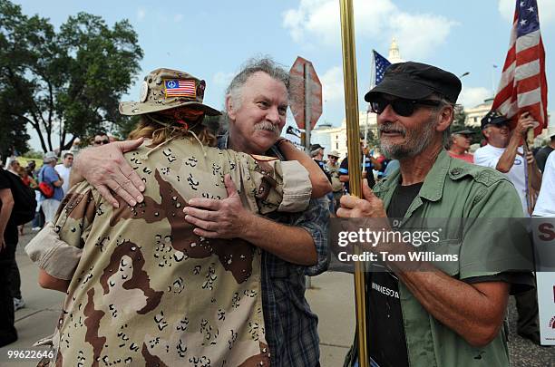 Vietnam veteran Joseph Johnson, center, hugs Persian Gulf veteran Chante Wolf, as Vietnam veteran Doug Drews looks on before the start of an an...