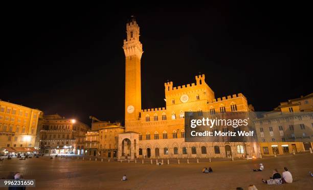 tourists at the palazzo pubblico with illuminated mangia tower and chapel, night, piazza il campo, siena, tuscany, italy - palazzo pubblico stock pictures, royalty-free photos & images