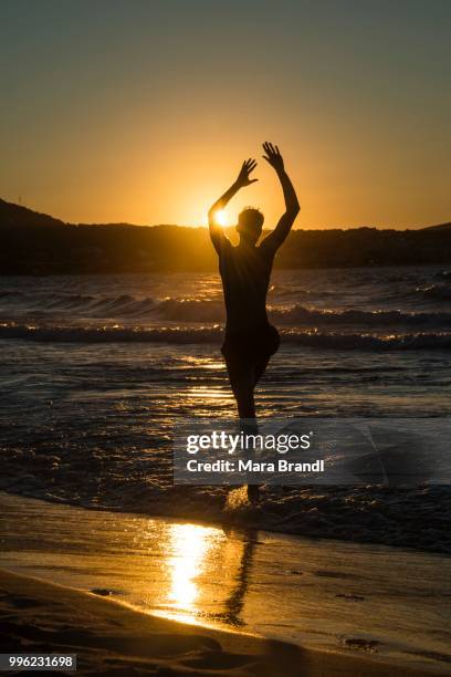 young man, silhouette, jumping on the beach at sunset, sunset by the sea, haute-corse, corsica, france - haute corse stock-fotos und bilder