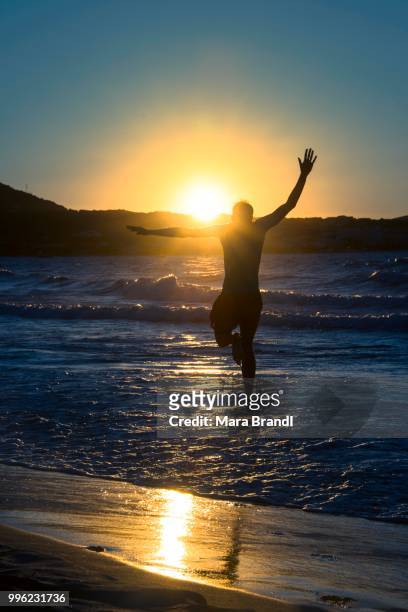 young man, silhouette, jumping on the beach at sunset, sunset by the sea, haute-corse, corsica, france - haute corse stock-fotos und bilder
