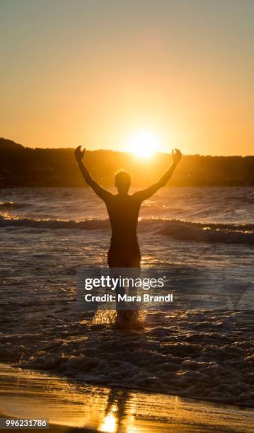 young man, silhouette, on the beach at sunset, sunset by the sea, haute-corse, corsica, france - haute corse stock-fotos und bilder