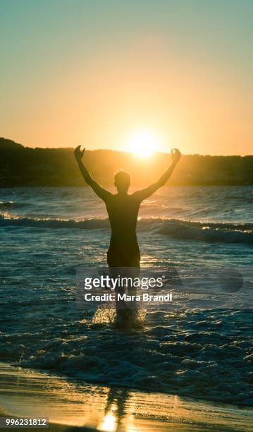 young man, silhouette, on the beach at sunset, sunset by the sea, haute-corse, corsica, france - haute corse stock-fotos und bilder