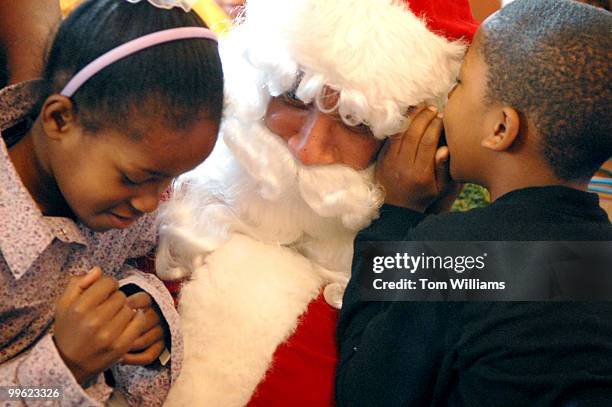 Tyjaun Palmer whispers into Santa's ear while his cousin Paulina Palmer sits on his lap during the 16th annual "D.C. Children's Christmas Party on...