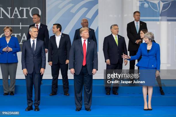 President Donald Trump reacts to British Prime Minister Theresa May while standing beside NATO Secretary General Jens Stoltenberg at the 2018 NATO...