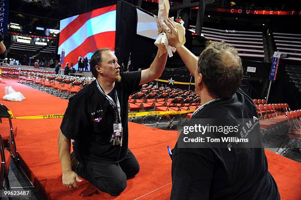 Rick Fisher wipes down a mirror on the base of a camera stand in preparation for the fourth day of the Republican National Convention held at the...