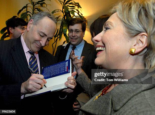 Sen. Chuck Schumer, D-N.Y., signs his new book "Positively American" for Sen. Hillary Clinton, D-N.Y., at a book signing reception at the Hunan...