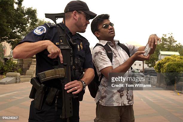Officer Jeff Fragala of the Capitol Police, checks out photos taken by Raj Sajja of Singapore as part of stepped up security measures, on the West...