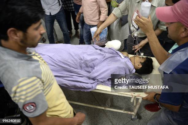An injured Kashmiri boy is carried on a stretcher at a hospital in Srinagar on July 11 where they were brought after being wounded in a blast after a...
