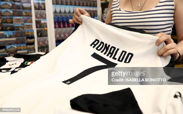 Picture taken on July 11, 2018 shows a saleswoman folding Cristiano Ronaldo's Juventus jersey in a shop in downtown Turin. - Portuguese football...