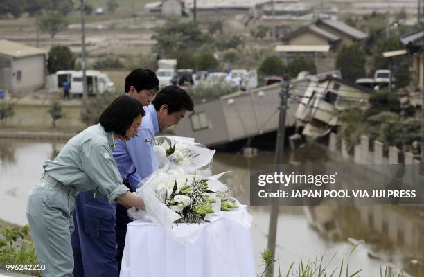 Japan's Prime Minister Shinzo Abe , Kurashiki City Mayor Kaori Ito and Okayama Governor Ryuta Ibaragi offer flowers ib the flood hit area Mabicho in...