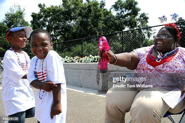 Jennitra Waters sprays Najeh Williams right and Wanye Waldburg before their church group, Rose of Sharon Ministries from Savannah, GA, performed in...