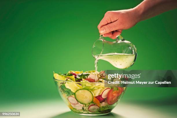 hand pouring herbal vinegar into a bowl filled with salad - dieta de alimentos crus imagens e fotografias de stock